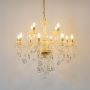 Crystal chandelier with gold detailing glowing brightly on white background for luxury decorative interior lighting.