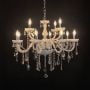 Elegant white chandelier with crystal accents illuminated against black background for luxury interior lighting.
