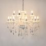 White chandelier with crystal accents glowing brightly on white background for luxury decorative home lighting.