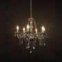 Elegant grey chandelier with crystal accents illuminated against black background for stylish interior decor.