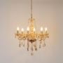 Golden chandelier with crystal droplets glowing brightly on white background highlighting elegant luxury design.