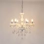 White chandelier with crystal detailing glowing brightly on white background for elegant luxury interior lighting.