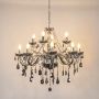Smoky crystal chandelier with silver accents illuminated on white background for luxury modern home lighting.