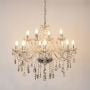 Golden chandelier with crystal design illuminated on white background highlighting luxury interior light piece.