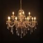 Golden chandelier with crystal detailing illuminated on black background for luxury home and hotel lighting.