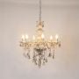 Golden chandelier with crystal droplets illuminated on white background for luxury decorative lighting.
