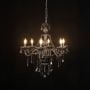 Chandelier illuminated with warm lights against a black background highlighting crystal design.