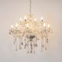 Chandelier with lights on glowing warmly with crystal details and elegant glass body on plain white background.