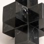 Closeup of black marble geometric sculpture showing detailed texture and smooth polished surface.