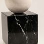 Closeup of marble geometric sculpture showing cube sphere and triangle shapes with polished artistic finish.