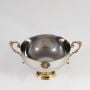 Silver decorative bowl with gold base handles and crest shown front-facing on white background for product display.
