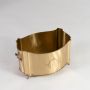 Empty gold metal oval planter with engraved emblem and side handles shown on a white background at an angle.
