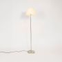 Elegant steel floor lamp with cream pleated fabric shade glowing warmly on plain white background.