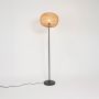 Contemporary black floor lamp with natural rattan woven shade glowing warmly on white background.
