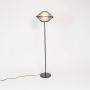 Contemporary black floor lamp with diamond shaped wire shade glowing warmly on white background.