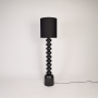 Floor lamp on white background with light switched off highlighting stacked black base details tall shade profile and clean contemporary lines.