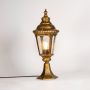 Golden pillar lamp glowing warmly with clear glass and bulb shown on white background for stylish outdoor garden lighting.