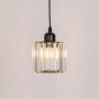 Glass pendant light with black metal fixture glowing warmly against plain white background.