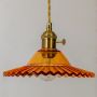 Closeup of amber ruffle glass pendant lamp showing detailed scalloped rim and golden holder with twisted cord.