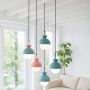 Set of pendant lights in pastel blue and pink matte metal with frosted glass globes creating a stylish modern home interior.