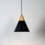 Stylish black pendant ceiling lamp with wood accent hanging over table for warm dining or cafe interior lighting.