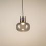 Grey glass hanging pendant light glowing gently on white background creating a warm and modern lighting look.