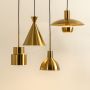 A modern set of metal pendant lights glowing warmly against a soft beige background each suspended at varied heights creating elegant contemporary interior décor.