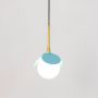 Blue pendant light with glass globe shade glowing warmly on white background for ceiling decor inspiration.