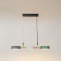 Wood and metal triple pendant light with grey white and green shades illuminated on a clean white background.