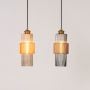 Pair of pendant lights with ribbed glass and brass finish glowing warmly for modern ceiling lighting design.