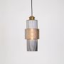 Pendant light with ribbed glass design and brass finish glowing warmly on white background for home lighting.