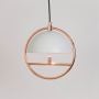 Rose gold pendant light with white dome shade glowing warmly suspended from ceiling on white background.