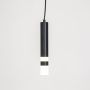 Sleek black cylindrical pendant light illuminated softly against plain white background for contemporary home interiors.