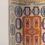Closeup of ceramic holder showing detailed geometric design in orange and blue with glossy golden rim.