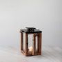 Wooden lantern with candle lit shown on white background for rustic home and patio lighting decor.
