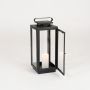 Black metal candle lantern with transparent glass panels displayed on white background ideal for indoor outdoor Decor use.