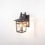 Black outdoor wall lantern light on white background showing bright bulb and clear glass panels.