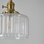 Closeup of ribbed glass pendant light highlighting brass holder and detailed glass texture for elegant interior lighting.