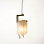 Glass drop pendant light turned on with brass frame and glass strands glowing softly against white background for modern interiors.