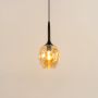Amber glass pendant light with black suspension rod for modern interior lighting.