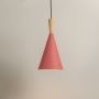 Minimalist cone pendant light in matte red finish with wooden top against white background for modern interiors.
