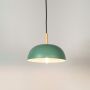 Green dome pendant ceiling light with wood top illuminated on white background for contemporary dining room and kitchen interior lighting.
