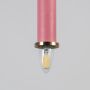 Closeup of pink pendant light with brass ring and clear bulb turned on showing detailed modern lighting design.