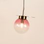 Pink glass pendant light glowing softly on white background showcasing artistic design perfect for dining and living room lighting.