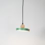 Green wood and metal pendant light glowing on white background with circular modern design for stylish interiors.