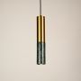 Green and gold marble and metal cylinder pendant light hanging against plain background with light off for luxury décor.