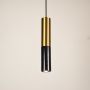 Black and gold marble and metal cylinder pendant light hanging against plain background with light off for minimalist modern décor.