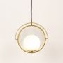 A modern gold ring pendant with a white spherical shade glowing softly against a clean white backdrop indicating the light is switched on.