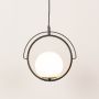 Black circular pendant light with round white globe shade shown with lights on highlighting its modern geometric frame design in a clean white setting.