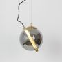 A warm amber globe pendant light with its rod light switched on creating a soft glowing effect while suspended against a white backdrop.